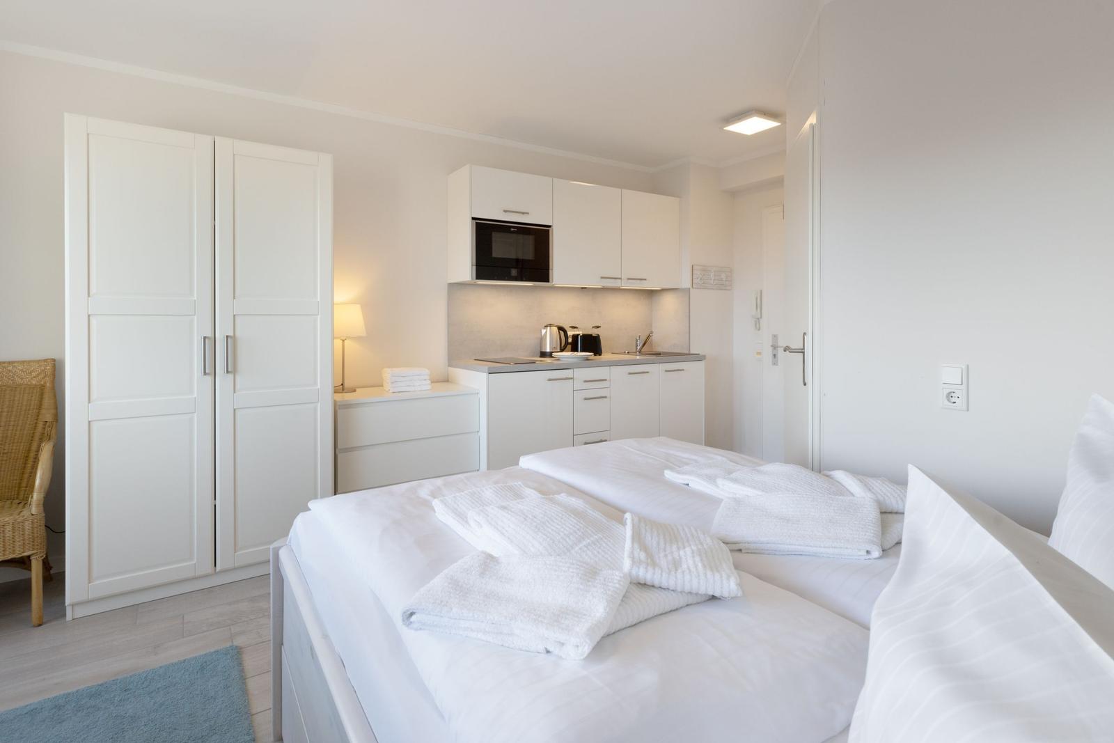 Zimmer mit Bett, Kleiderschrank und kleiner Küche.