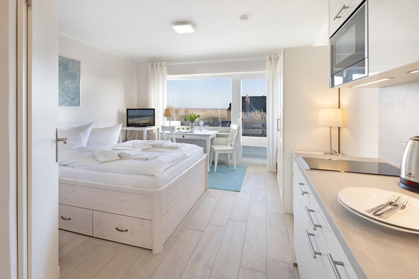 Schlafzimmer mit Bett, Tisch und Aussicht auf die Landschaft.