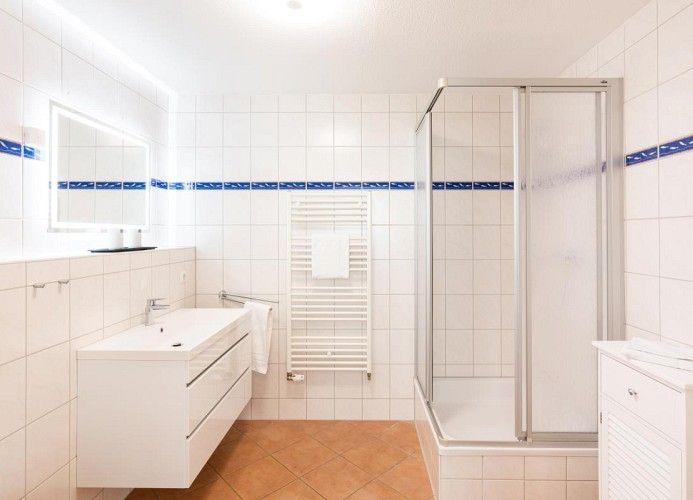 Badezimmer mit Dusche, Waschbecken und Heizkörper