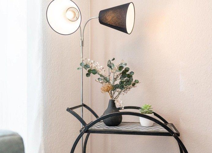 Hochwertige Stehlampe neben einem Tisch mit Pflanzen und Dekoration.