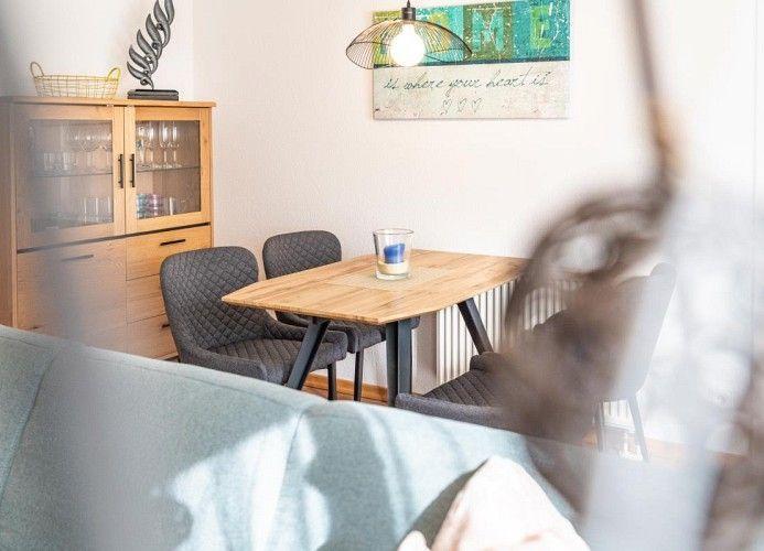 Essbereich mit Holztisch, Stühlen und Glasvitrine an der Wand.