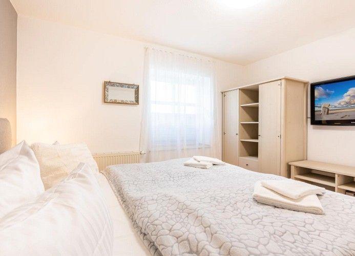 Schlafzimmer mit Bett, Kleiderschrank und Fernseher an der Wand.