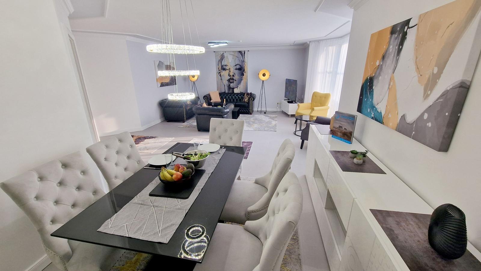 Esszimmer mit Esstisch und Stühlen. Wohnzimmer mit Sofa, Sessel und Wandbild.