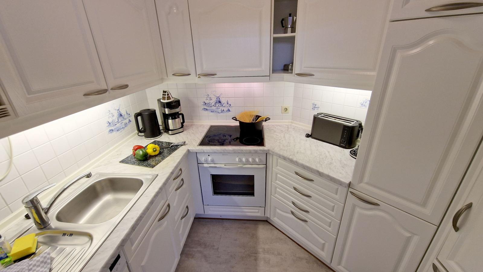 Küche mit weißen Schränken, Marmorarbeitsplatte und Edelstahlspüle.