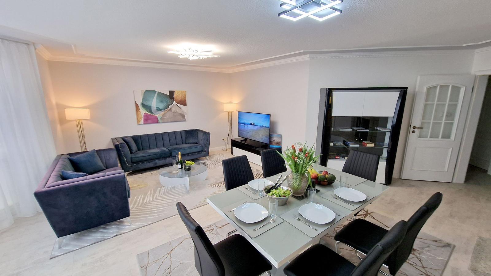 Wohn- und Essbereich mit Sofa, Esstisch und TV.