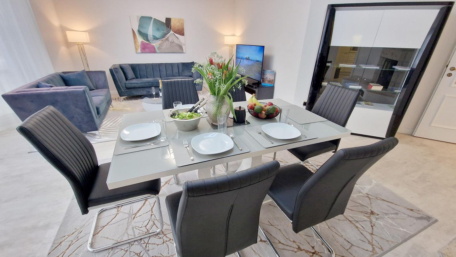 Esstisch mit Stühlen, Sofa und Fernseher im Wohnbereich.