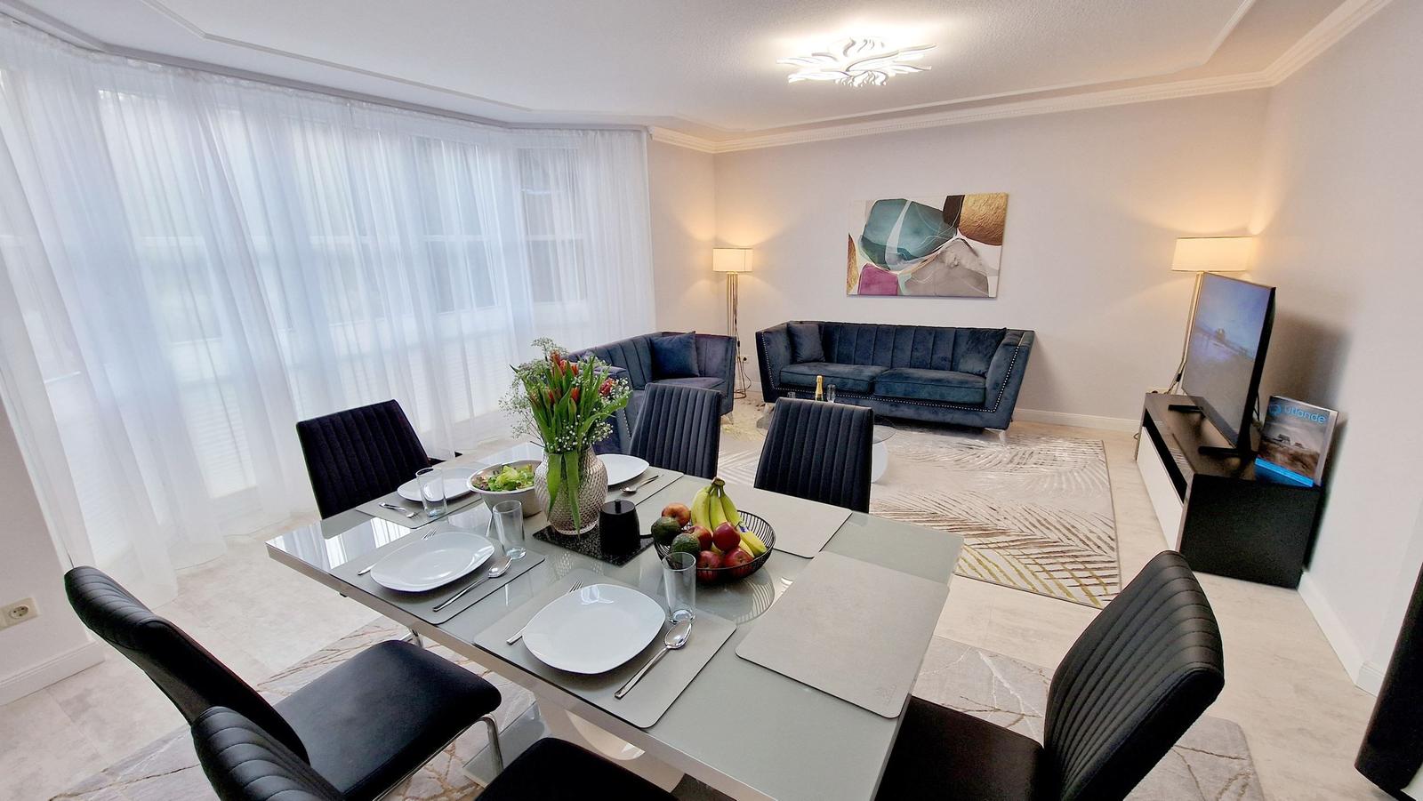 Essbereich mit Tisch und Stühlen. Wohnbereich mit Sofa und Fernseher.