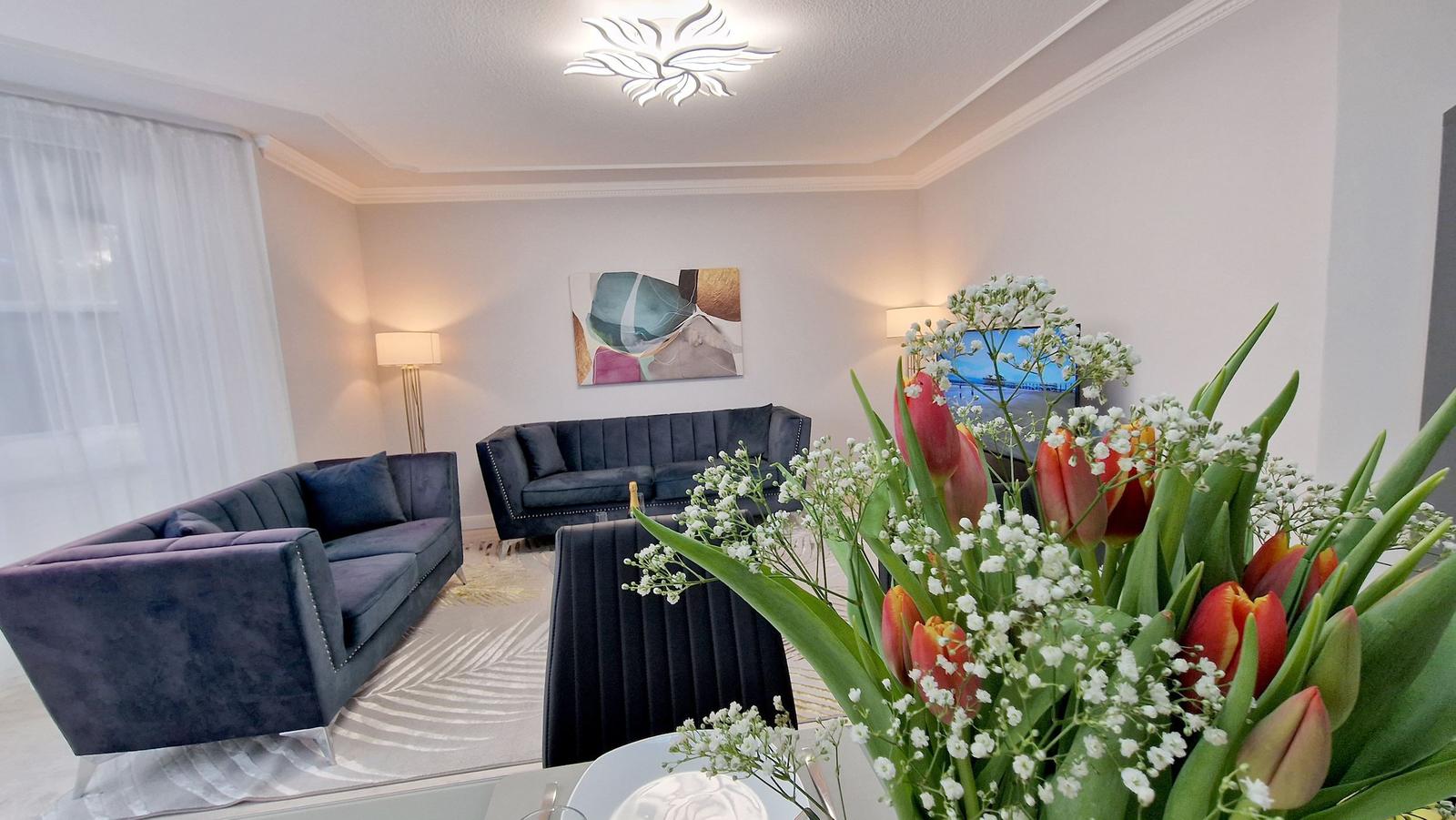 Wohnzimmer mit zwei Sofas, Wandbild und Blumenstrauß im Vordergrund.