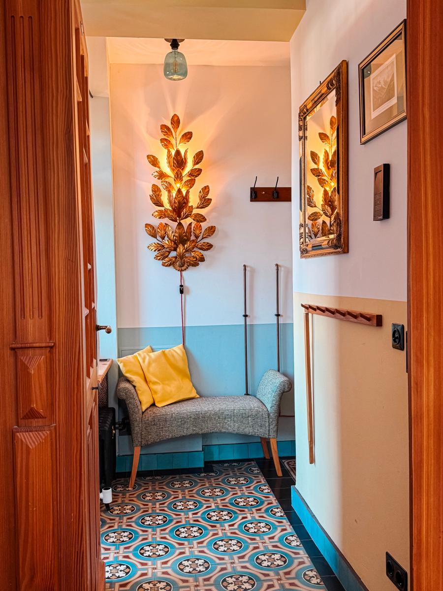 Eingangsbereich mit Bänkchen, Wandlampe und Mosaikboden.