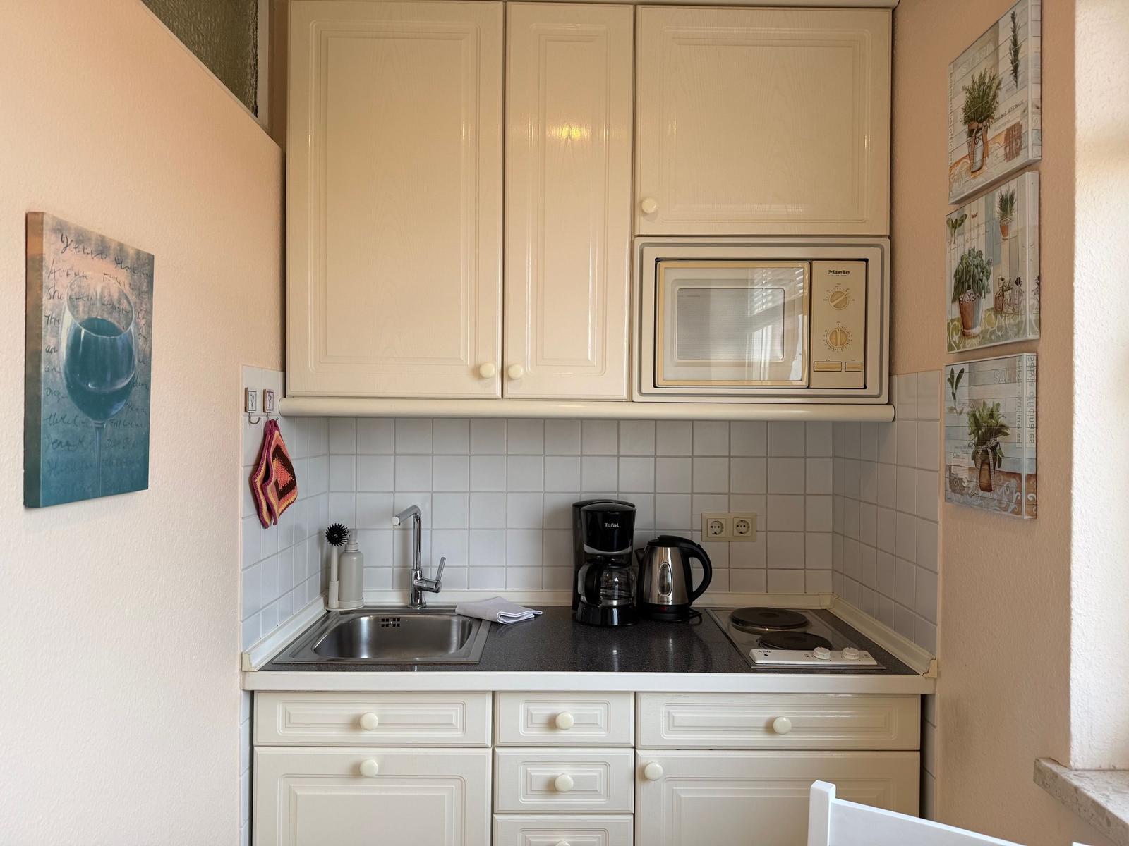 Küche mit Arbeitsplatte, Spüle, Mikrowelle und Kochfeld.