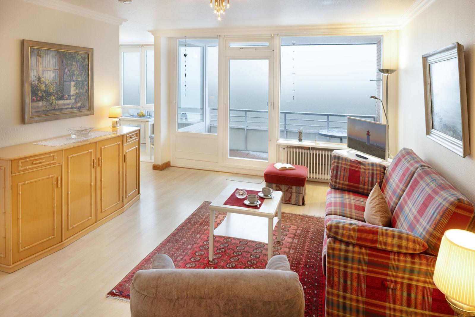 Wohnzimmer mit Sofa, Couchtisch und Blick aufs Meer.