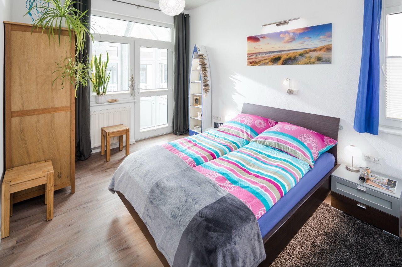 Schlafzimmer mit Bett, Nachttisch, Kleiderschrank und Fenster.