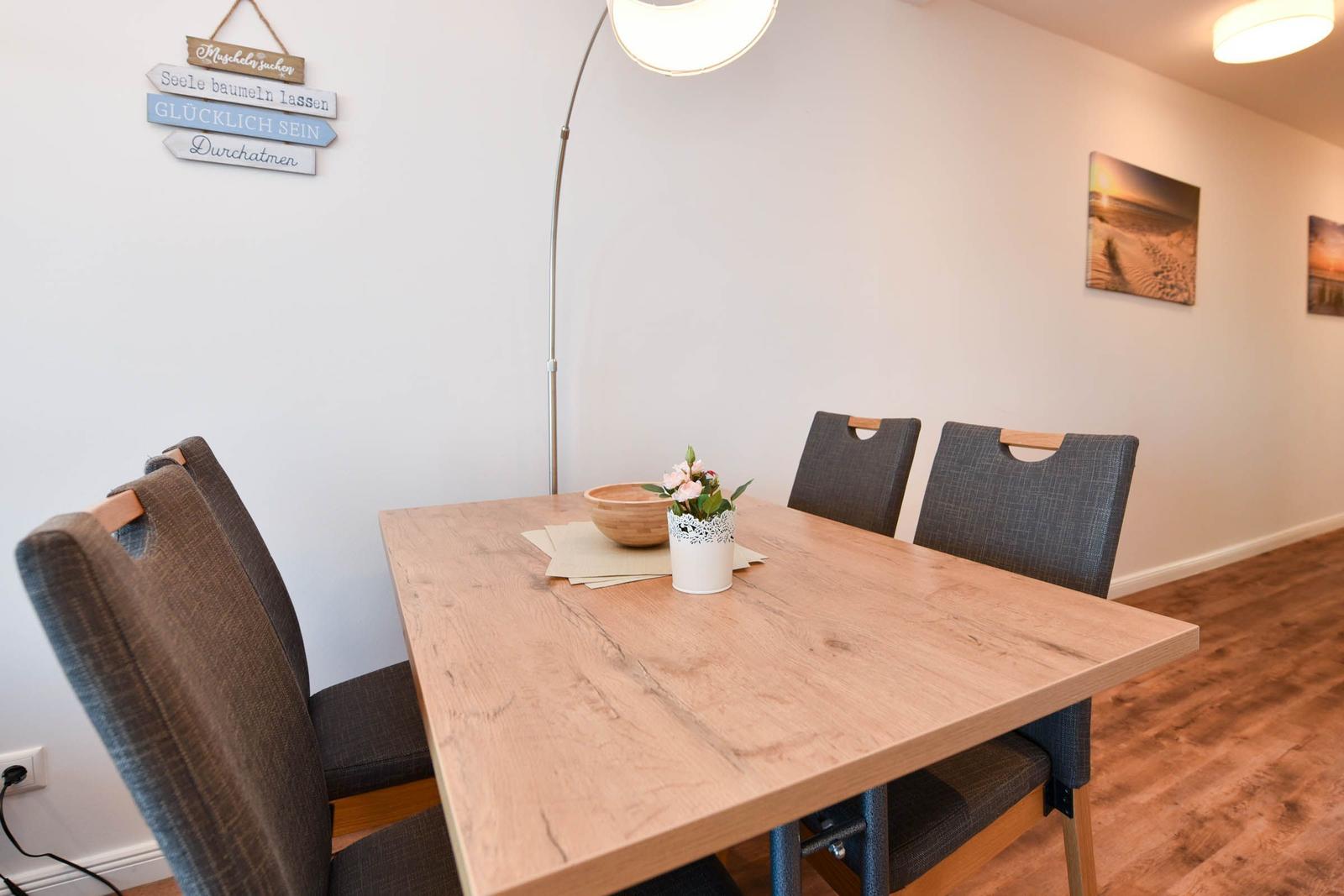Esszimmer mit Holztisch, vier Stühlen und Wanddekoration.