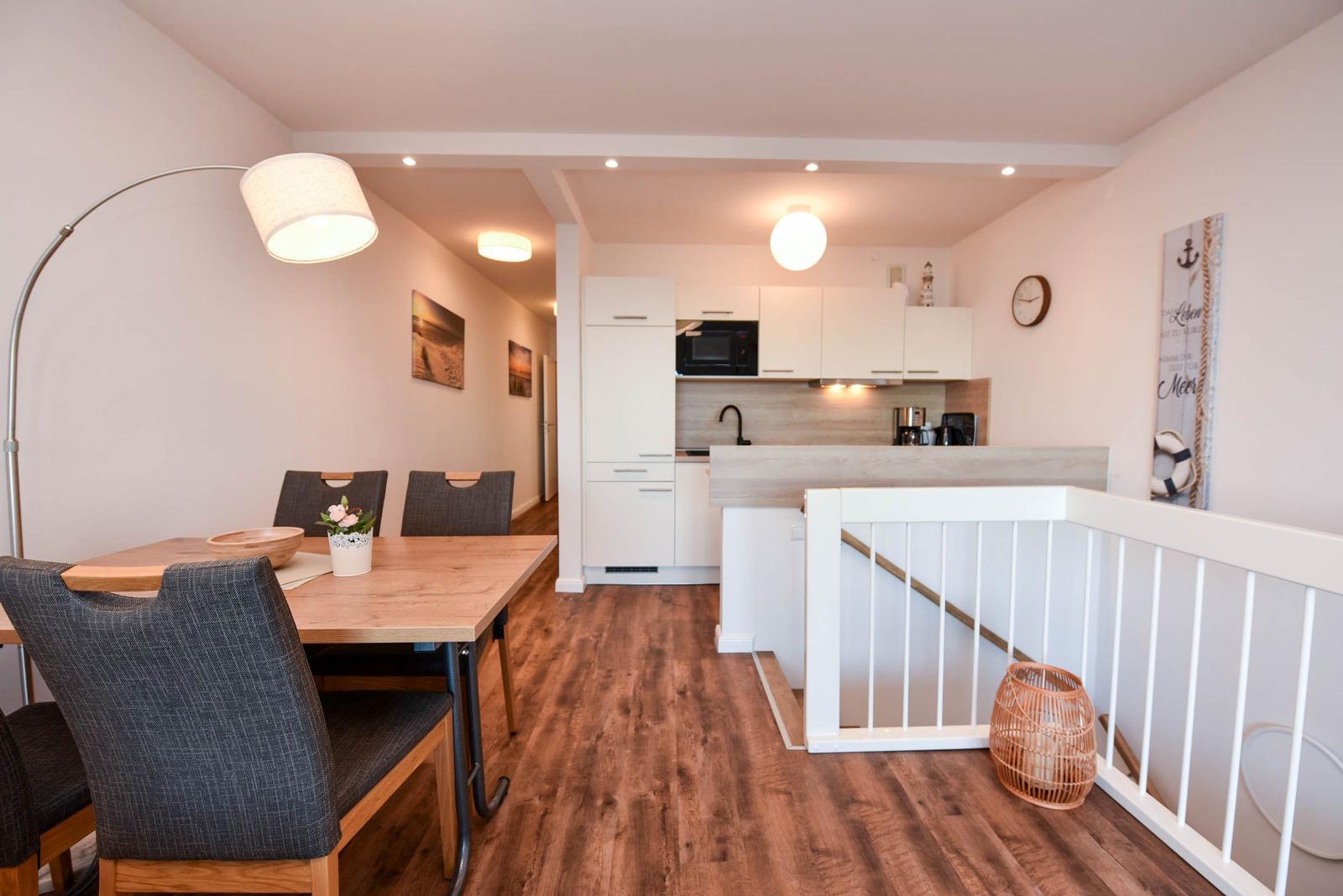 Essbereich mit Tisch und Stühlen, Küche mit Arbeitsplatte und Küchenschränken, Boden aus Holz