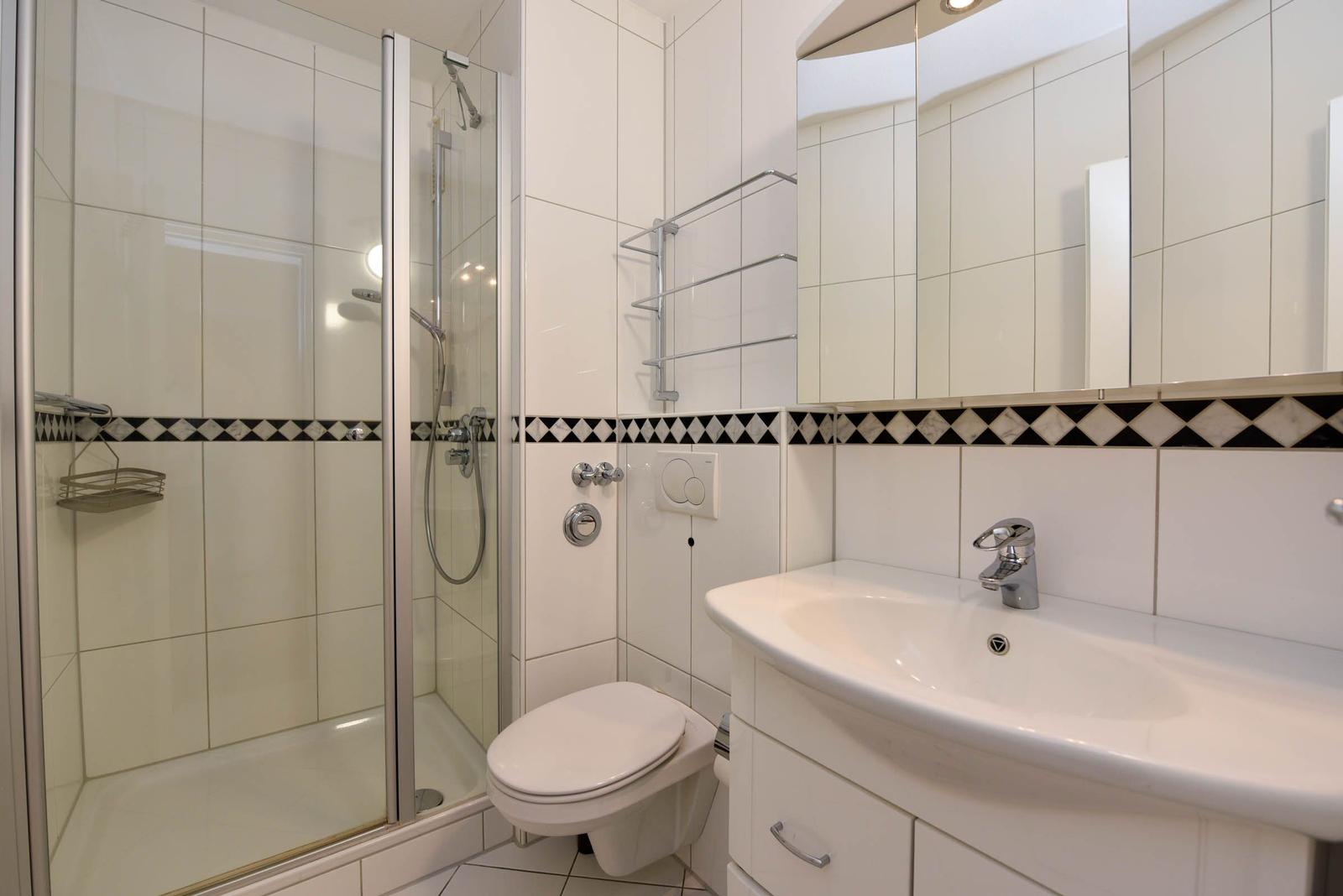 Badezimmer mit Dusche, Toilette und Waschbecken.