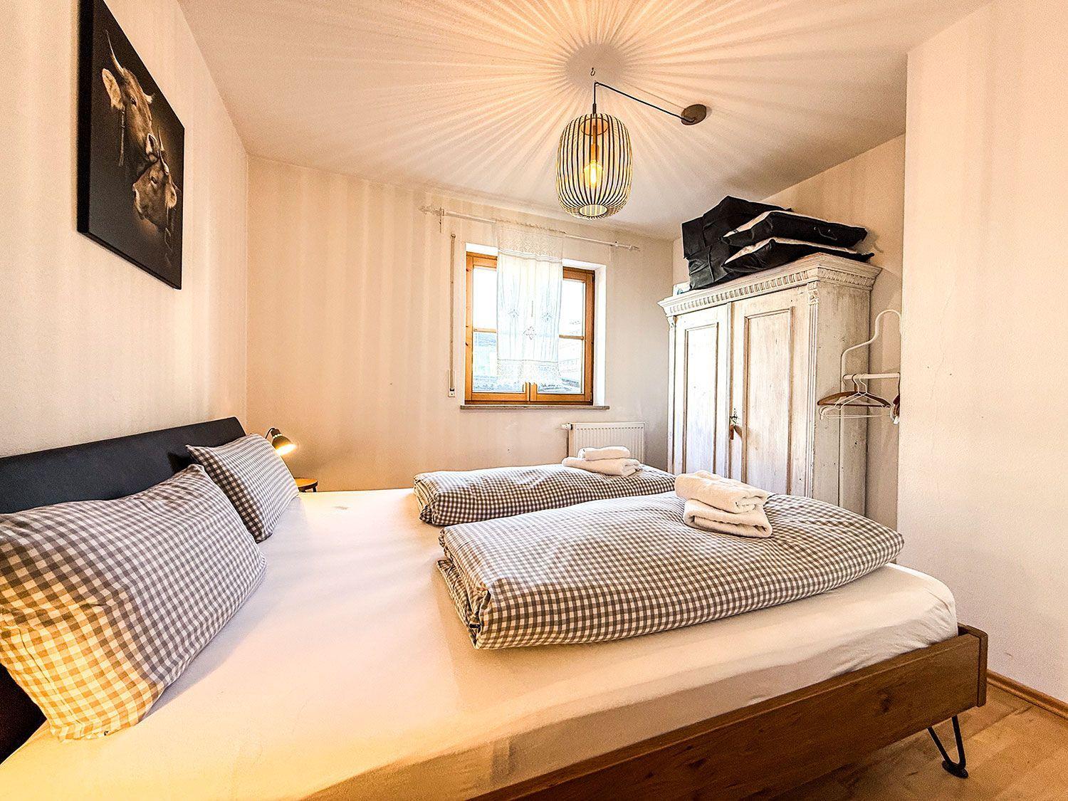 Schlafzimmer mit Doppelbett, Fenster, Kleiderschrank und Decke.