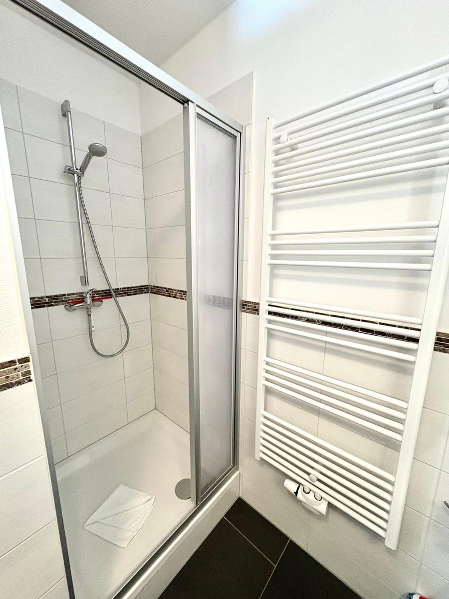 Dusche mit Duschbrause und Heizkörper an der Wand.