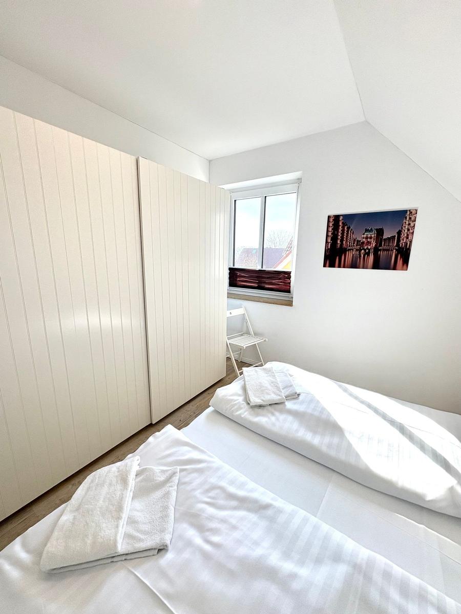 Zwei Betten mit weißen Bettwäschen, ein Fenster und ein Bild an der Wand.