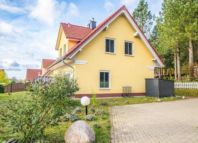 Ein gelbes Haus mit rotem Dach, umgeben von Grün und einem gepflasterten Weg.