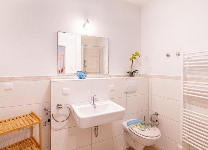 Badezimmer mit Waschbecken, Spiegel, Toilette und Heizkörper.