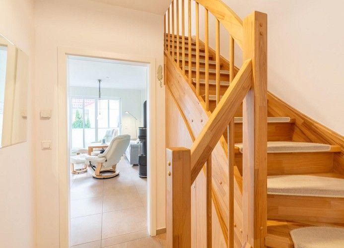 Holztreppe mit Teppichstufen führt zu einer offenen Wohnfläche mit Sitzgelegenheit.