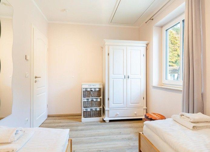 Zwei Betten, weißer Kleiderschrank und Fenster mit Blick nach draußen.