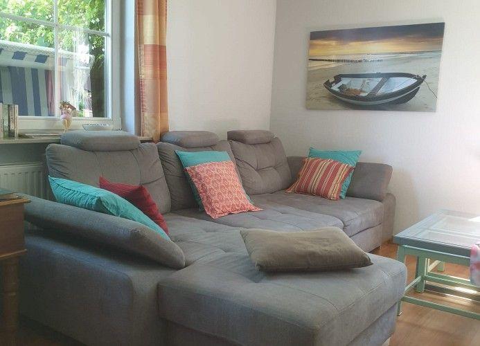 Großes Sofa mit Kissen, Wandbild und Fenster mit Blick nach draußen.