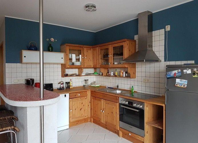 Küche mit Holzschränken, Edelstahlherd und Kühlschrank
