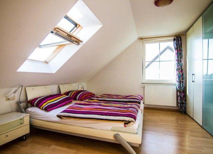 Schlafzimmer mit Dachschräge, Dachfenster, Bett und Kleiderschrank.