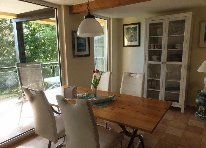Esstisch mit Stühlen, Glasfrontschrank und Blick auf Balkon
