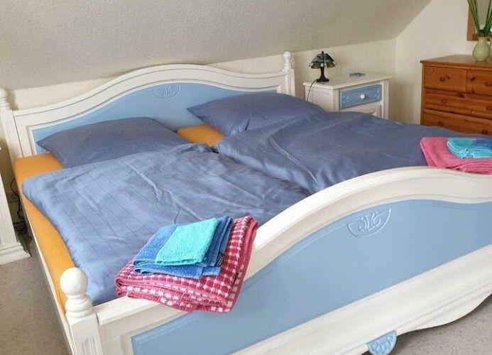 Doppelbett mit blauer Bettwäsche und gefalteten Handtüchern