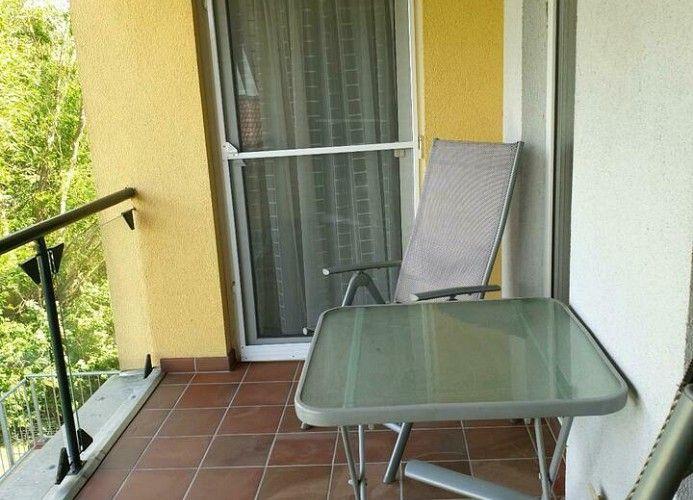 Terrasse mit Tisch, Stuhl und Blick auf grüne Vegetation.