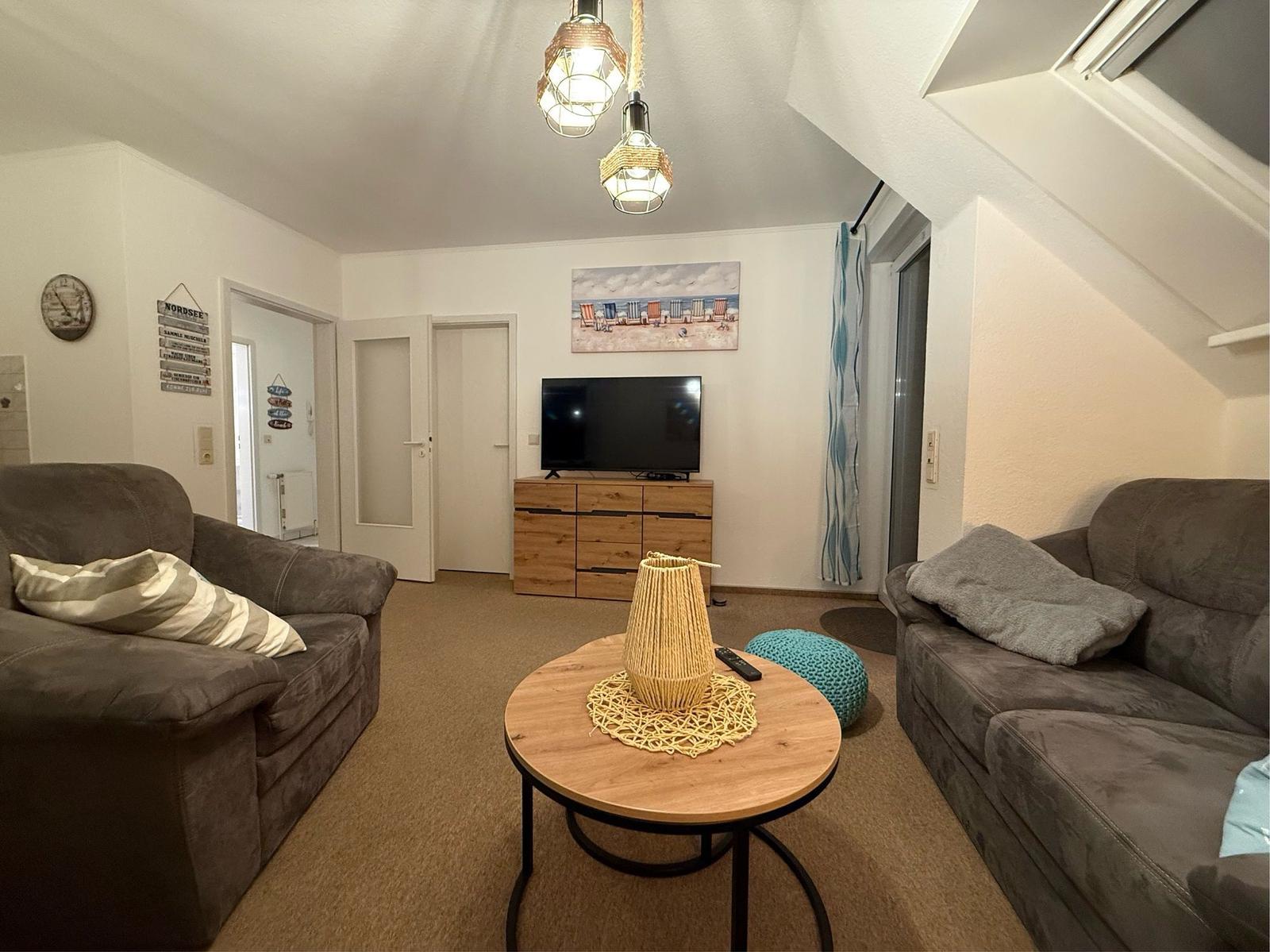 Wohnzimmer mit zwei Sofas, runden Tisch und Fernseher an der Wand.