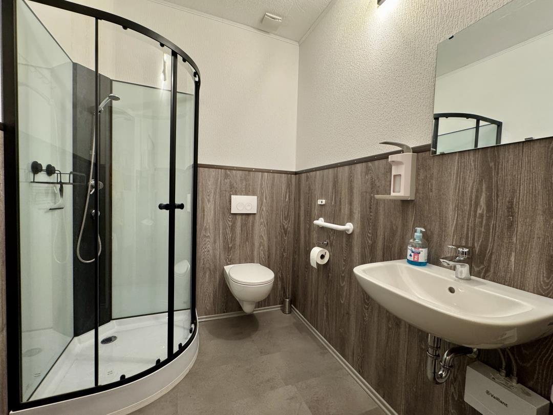 Badezimmer mit Dusche, WC und Waschbecken.