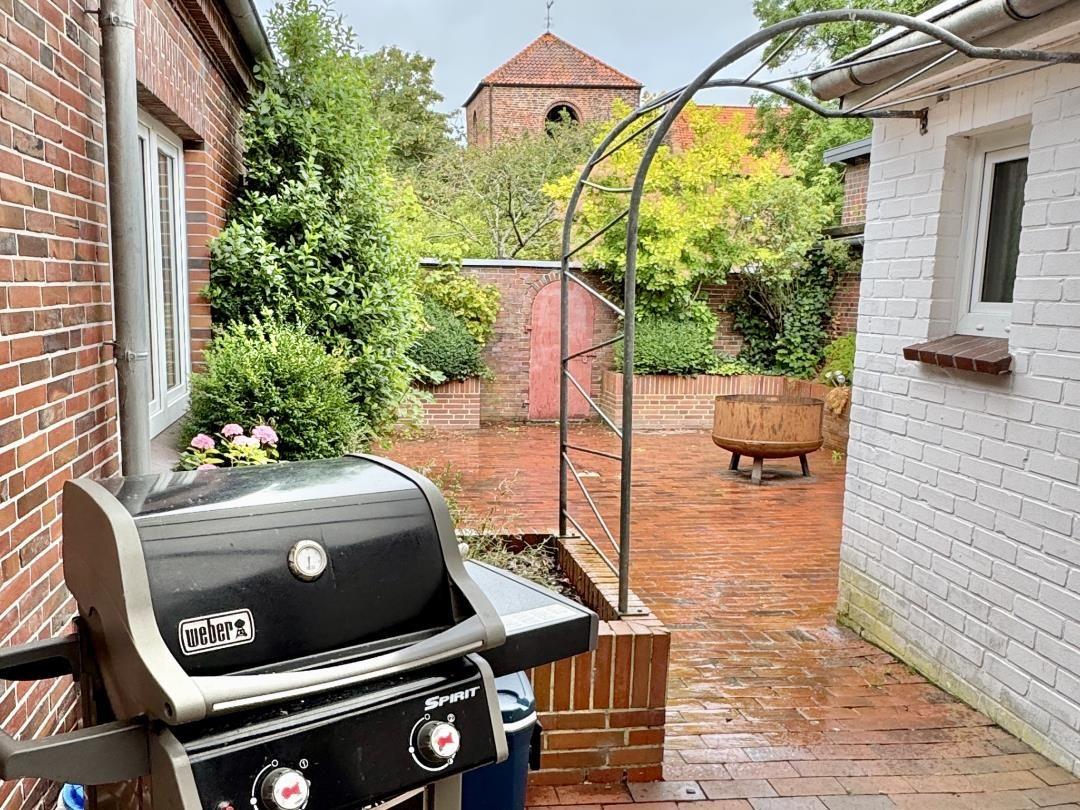 Terrasse mit Grill, Pflanzen und Blick auf eine Kirche