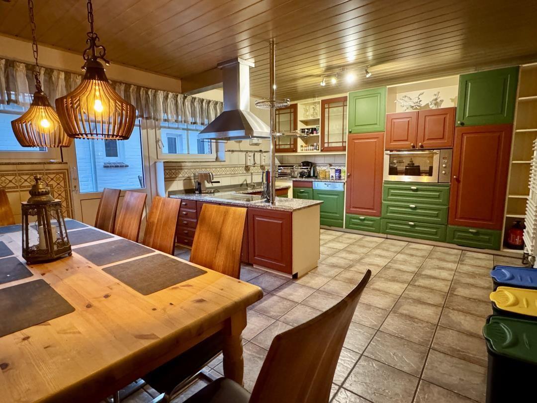 Küche mit Essbereich, grün-rot lackierten Schränken und Holztisch mit Stühlen.