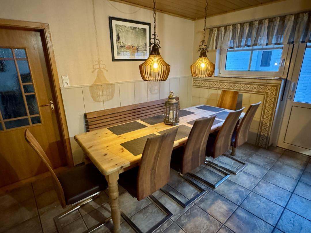 Esszimmer mit Holztisch, Stühlen und zwei Hängelampen über dem Tisch.