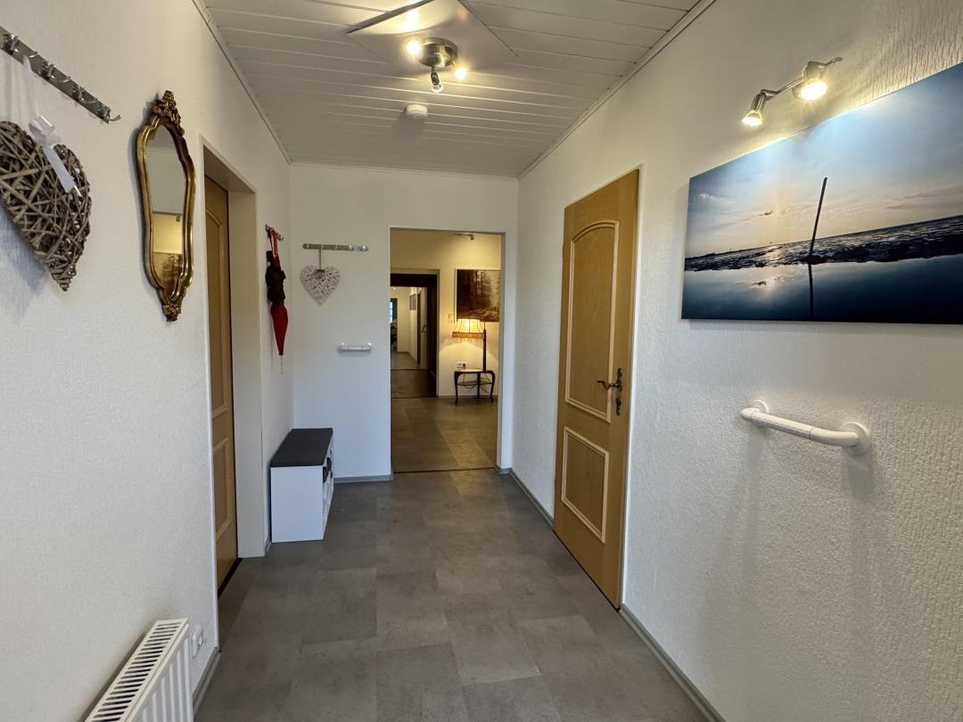Flur mit Tür zu Wohnbereich, Wandbild und Handlauf an der Wand.