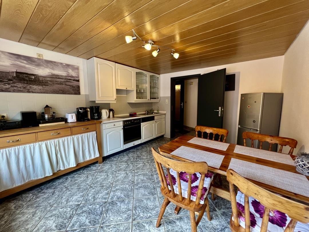 Küche mit Essbereich, Holztisch, Stühle und Kühlschrank