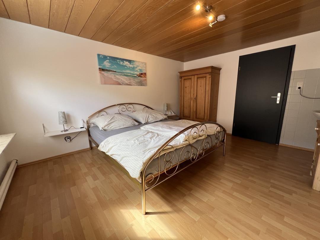 Schlafzimmer mit Doppelbett, Holzboden und Wandbild. Holzdecke und Kleiderschrank.