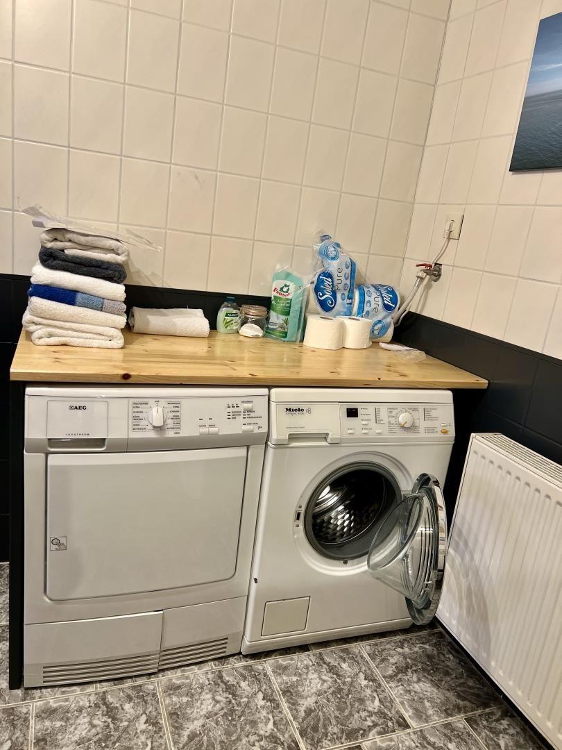 Wäscherei mit Waschmaschine und Trockner sowie Handtüchern und Reinigungsmitteln.