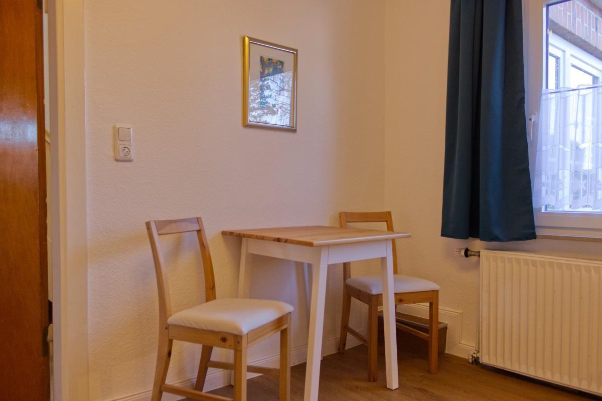 Essbereich mit Tisch, zwei Stühlen und Fenster mit Vorhang.