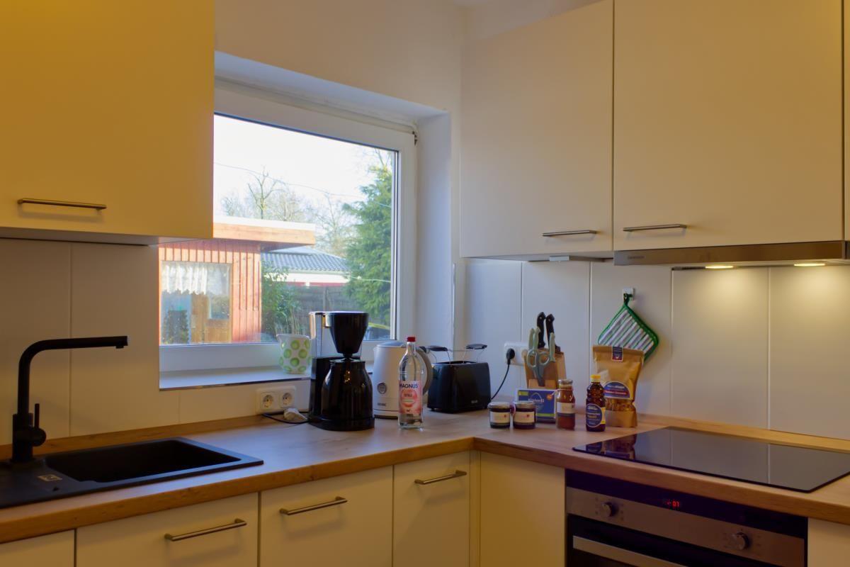 Küche mit Arbeitsplatte, Spüle, Kochfeld und Fenster.