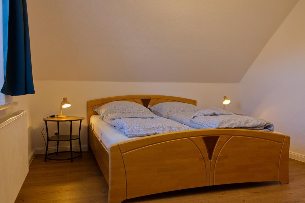 Ein Schlafzimmer mit einem Holzbett, zwei Nachttischen und einer geneigten Decke.