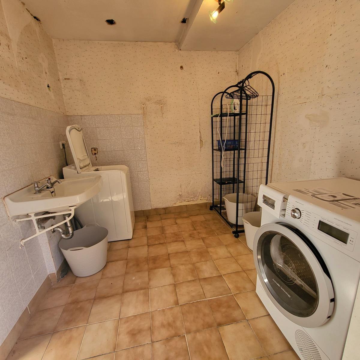Waschraum mit Waschmaschine, Trockner und Waschbecken.