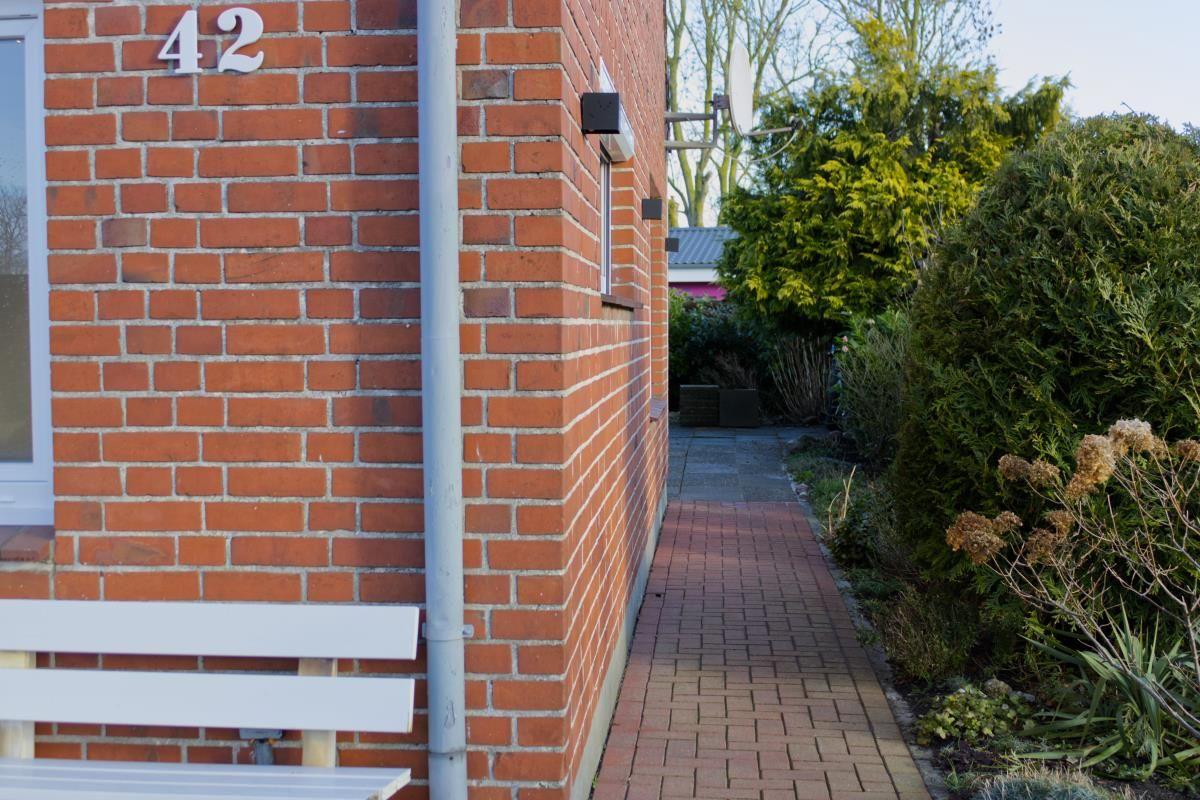 Haus mit rotem Backsteinfassade, weiße Bank und gepflasterte Gartentreppe.