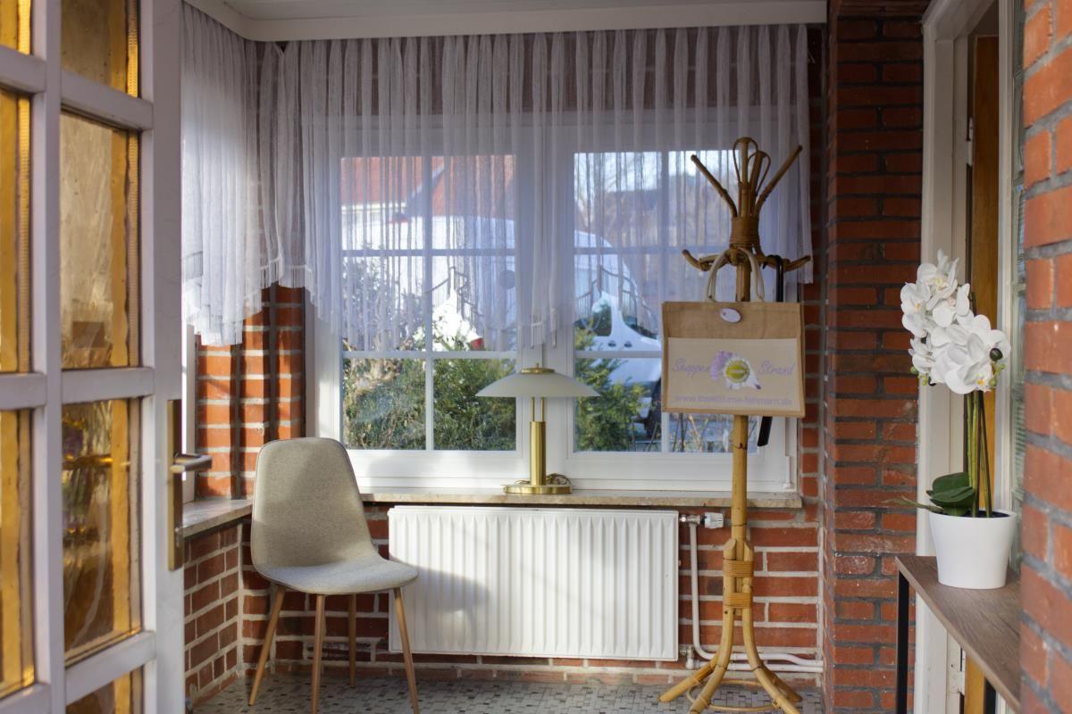 Ein Raum mit Fenster, Stuhl, Lampe und Pflanze an einer Backsteinwand.