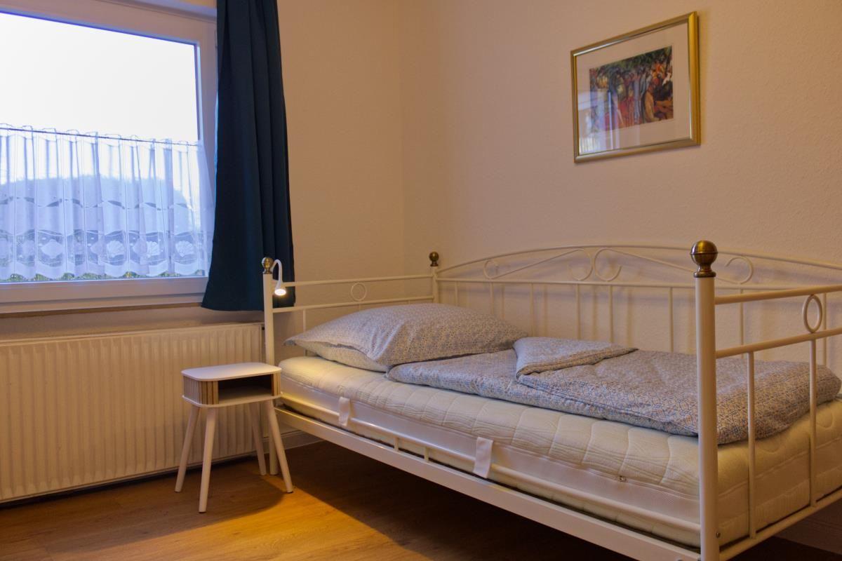 Ein Schlafzimmer mit Bett, Nachttisch und Fenster mit Vorhängen.