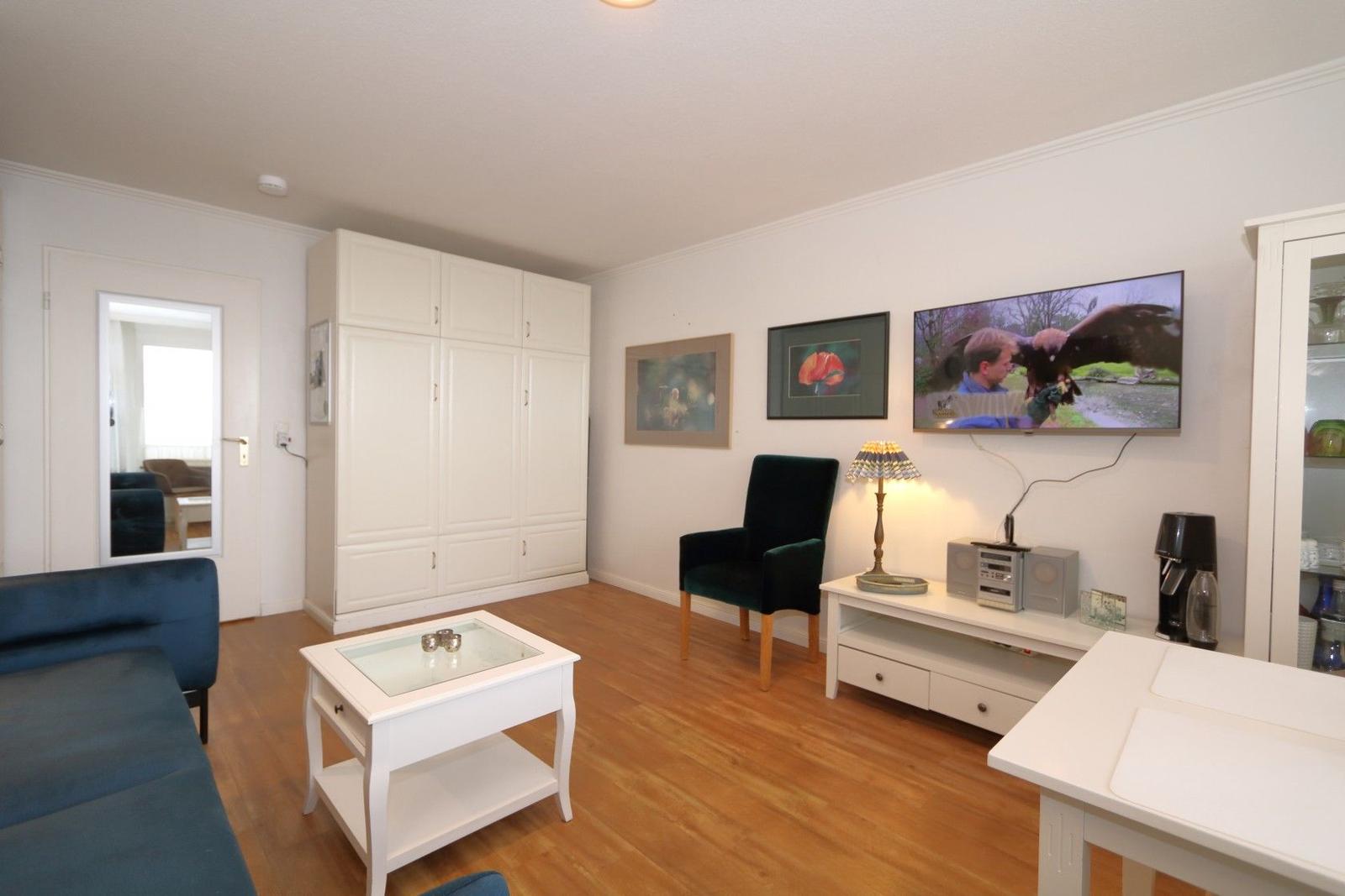 Wohnzimmer mit Sofa, Stuhl, Fernseher und Holzboden.