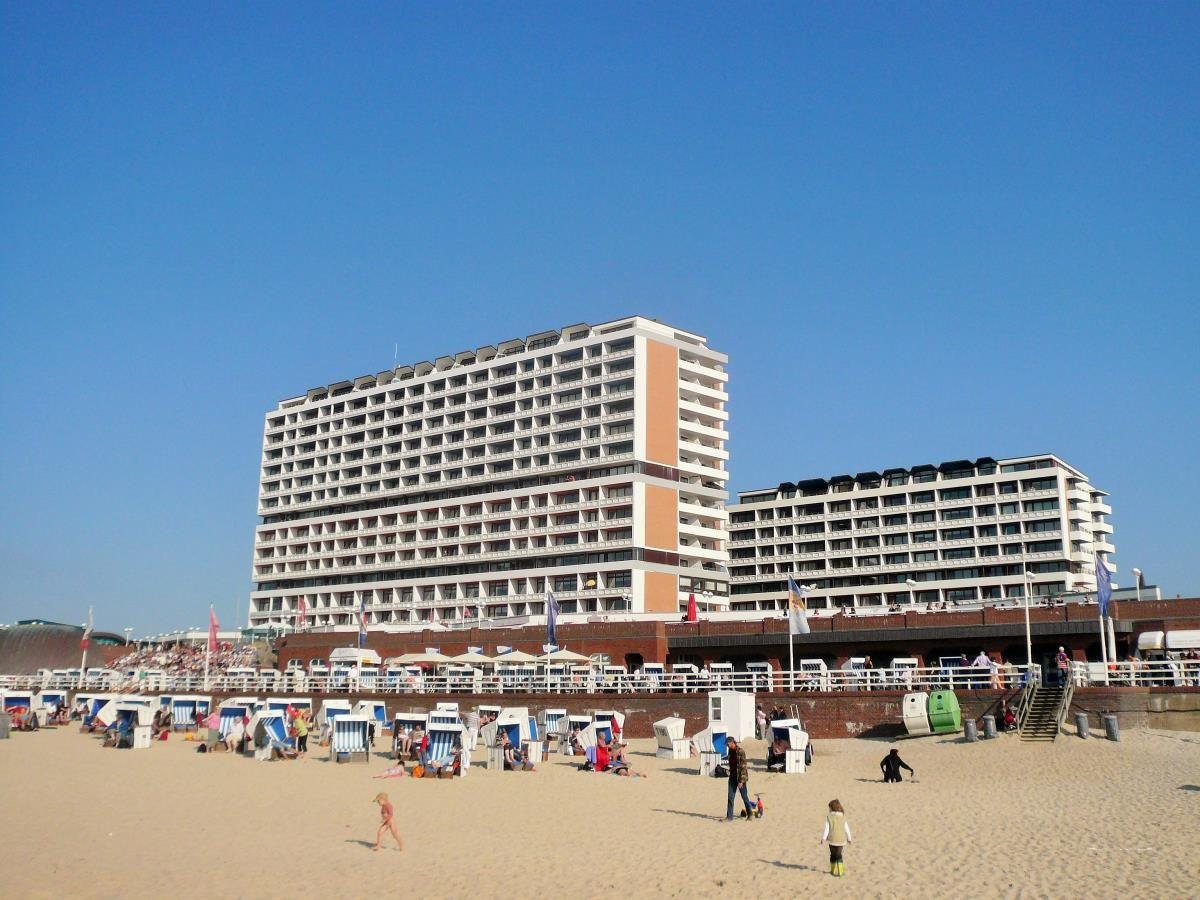 Strand mit Strandkörben und großem Hotelgebäude im Hintergrund.
